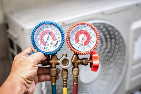 HVAC technician holding a manifold gauge set for HVAC repair in Knoxville, TN