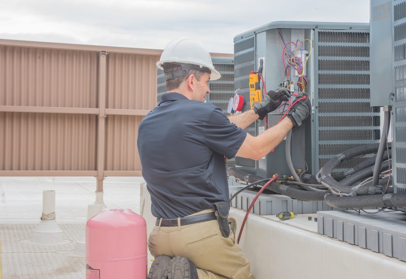 An expert from Grissom Heat & Air fixing the thermostat for residential use in Knoxville, TN 